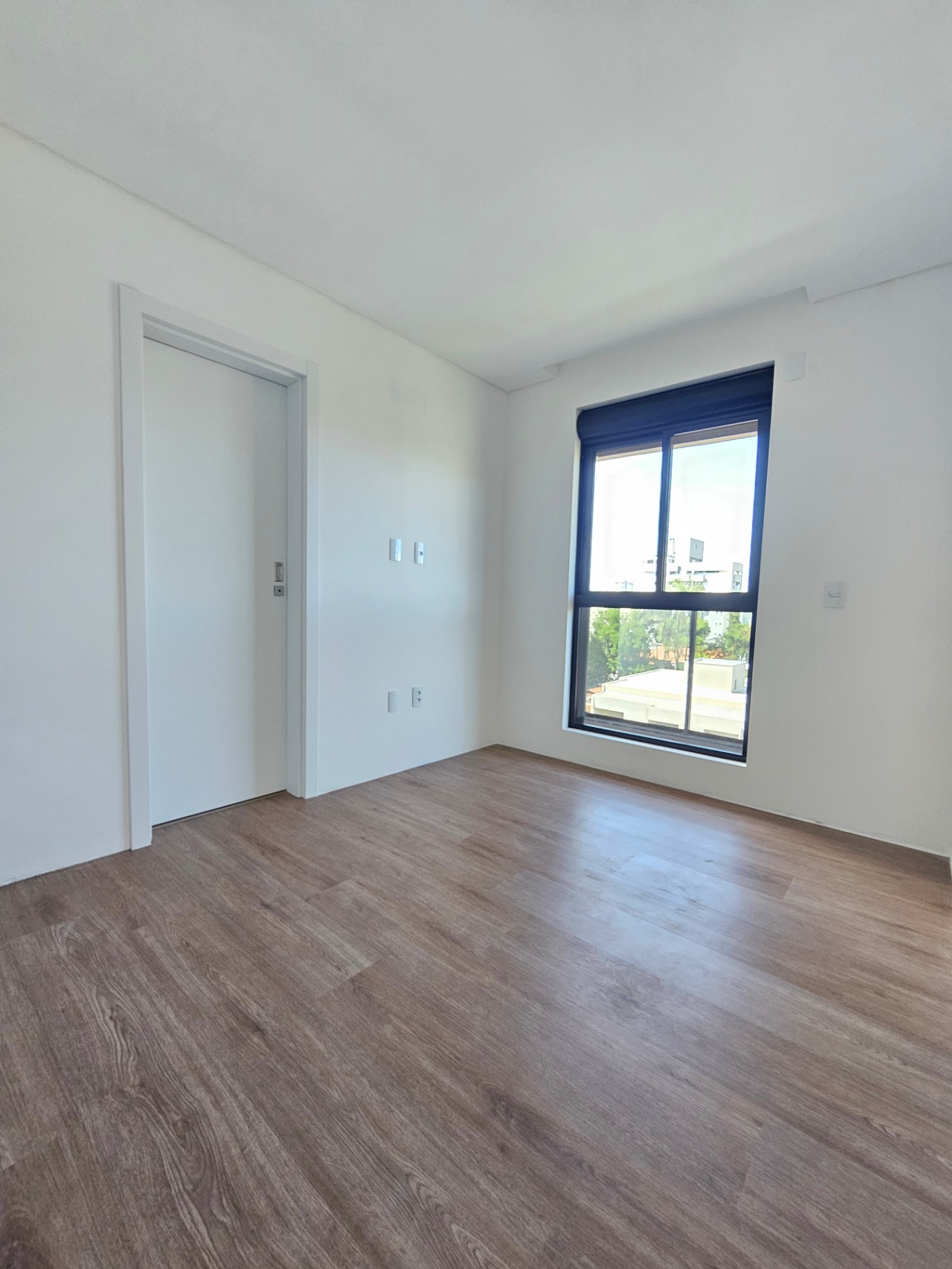 Dormitório com piso amadeirado e janela ampla — Residencial Bled